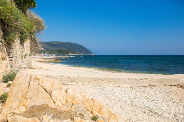 Harika manzarası kayalık sahil ve mavi gökyüzü ile güneşli bir günde güzel kumlu plajı. Pitoresk ve muhteşem sahne. Güzel bir plaj Ouranoupolis, Yunanistan