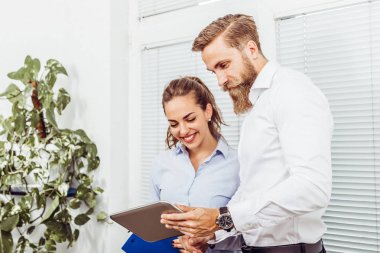 Mutlu genç meslektaşları stading dijital tablet kullanma ve ofis projesinde konusunda konuşurken coworking Office görüntü.