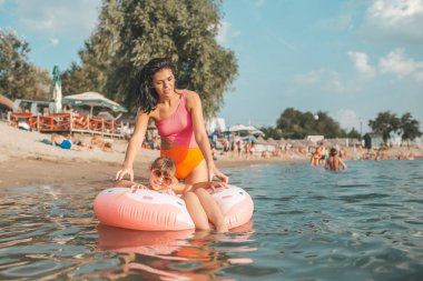 Anne ve kızı yüzme ve su şişme bir çörek üzerinde rahatlatıcı. Yaz tatili