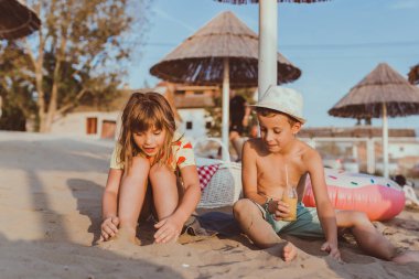 Sahilde bir havlu üzerinde oturan ve konuşmak mutlu pozitif çocuk.