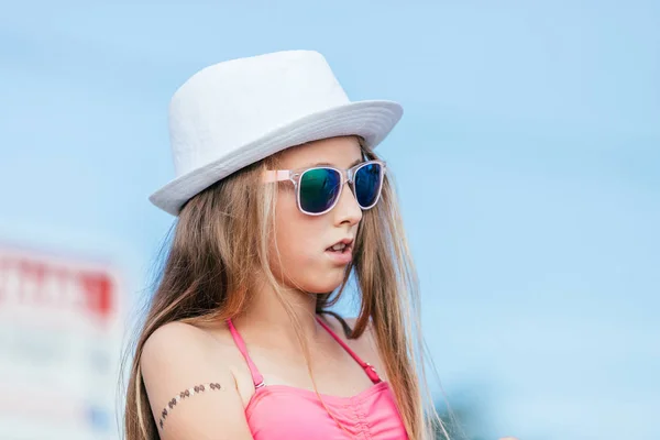 一个快乐的女孩在海滩上戴着帽子和太阳镜的肖像 — 图库照片