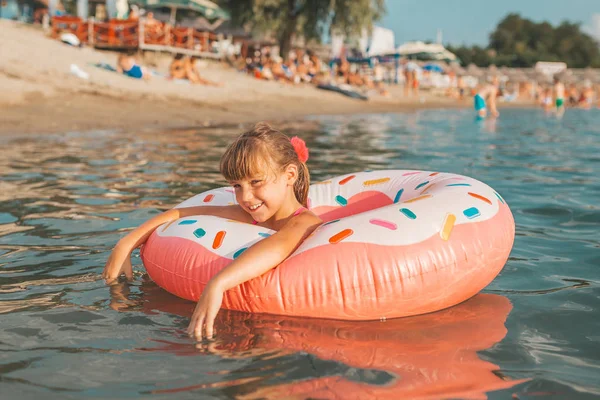 炎热的夏天 快乐的小女孩带着充气戒指在水中游泳 孩子们学习游泳 儿童水玩具 — 图库照片