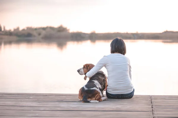 Genç ve güzel kadın köpeğini Basset Hound Nehri üzerinde ahşap iskelede sarılma