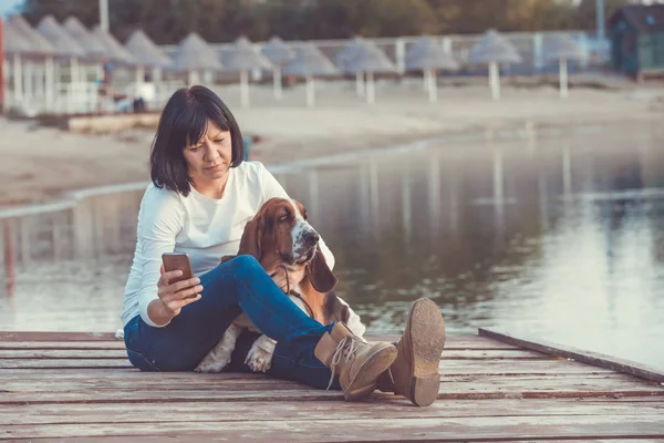 Портрет Красивої Молодої Жінки Своєю Собакою Використовуючи Мобільний Телефон Сидячи — стокове фото