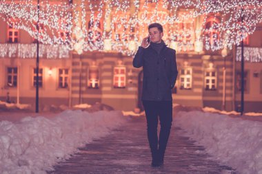 Cep telefonunuzda geceleri dekore edilmiş şehirde sokak konuşan yakışıklı adam. -IMAG