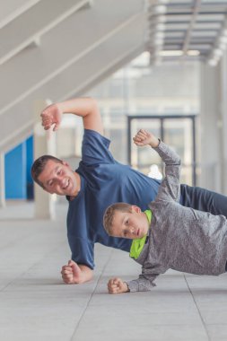 Küçük bir çocuk ve babası birlikte bir spor merkezinde egzersiz. Baba ve oğul birlikte vakit ve sağlıklı bir yaşam tarzı yol. Birlikte çalışma dışarı. Fitness gün. Sportif aile kavramı. Aktif yaşam tarzı