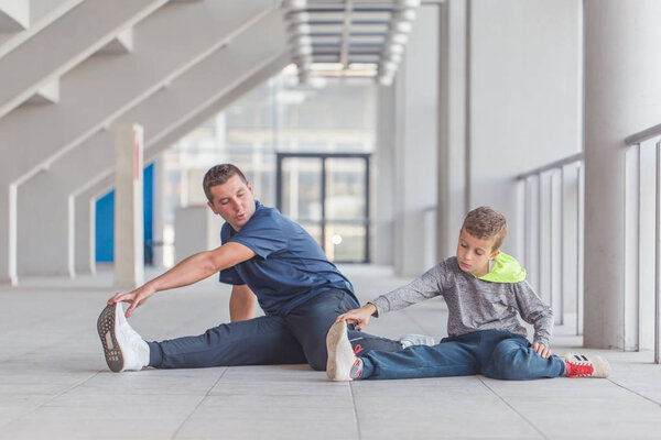 Little boy and his father exercising together at a sports center. Father and son spend time together and lead a healthy lifestyle.Working Out Together. Fitness Day. Sporty Family Concept. Active Lifestyle