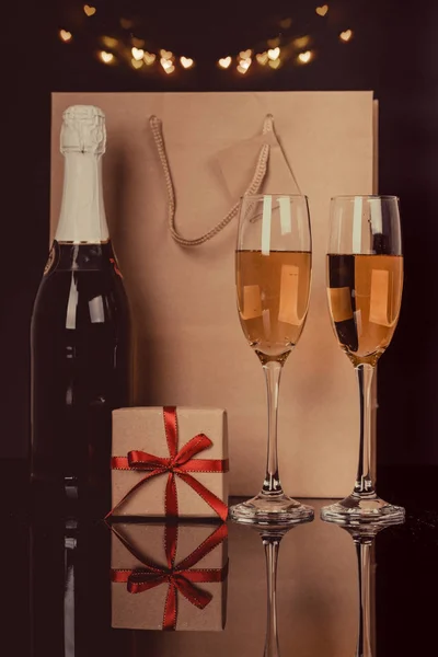 Champagnerflasche Zwei Weingläser Und Geschenk Einer Papiertüte Auf Schwarzem Hintergrund — Stockfoto