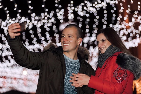Happy young loving couple making selfie and smiling while standing in the city  at night - Imag