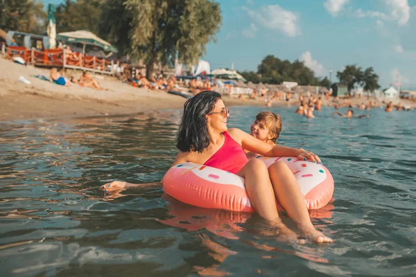 Mom and daughter swiming and relaxing in the water on an inflatable donut. Summer holiday