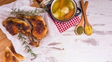 Rustik ahşap arka plan üzerinde geleneksel bir kase lezzetli kızarmış tavuk budu biberiye ve kaşık ve tavuk çorbası içinde baharatlar ile servis. Yukarıdan görüntüleyin. Kopya alanı