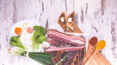 Tabak kızarmış yumurta ve domuz pastırması, kızarmış ekmek, salata ve baharat ahşap rustik arka plan üzerinde. Çok lezzetli yemek. Üstten görünüm. Kopyala Yapıştır