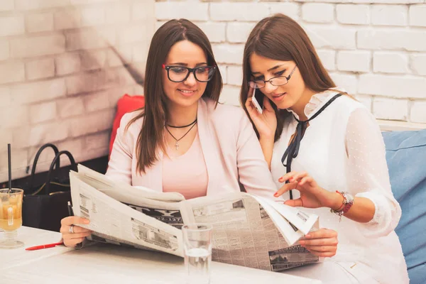 Unemployed, smiling woman is looking for a job in the newspaper and calling. Her best friend helps her to find the right job for yourself  - Image