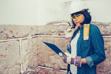 Kadın inşaat işçisi planlama nasıl olumlu tutum ile banyo boruları tamir için. bir iş aracı kullanarak.