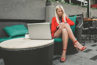 Açık havada çalışan. Dizüstü bilgisayarda çalışan ve onun izle güzel açık Cafe zamanında kontrol oldukça genç iş kadını.