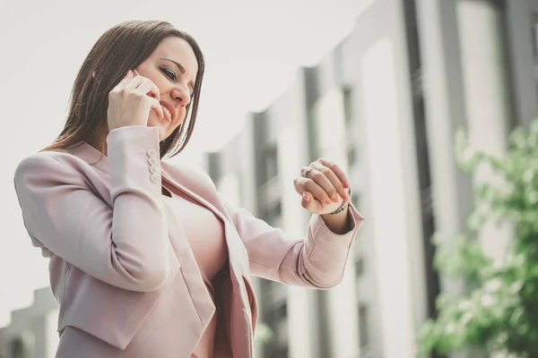 Happy business woman talking on phone and checking the time on the watch. - Image