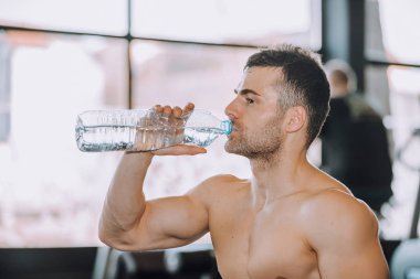 İçme suyu bir şişe bir spor salonunda yakışıklı genç adam