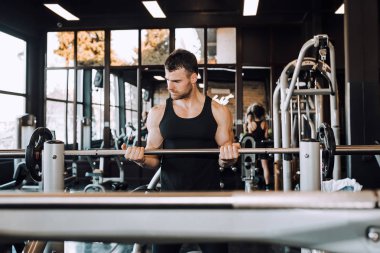 Bir spor salonunda barbell ile kas vücut ile genç adam