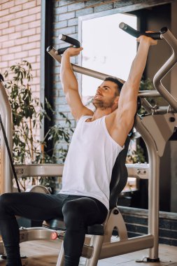Makine üzerinde spor salonunda eğitim genç vücut geliştirmeci