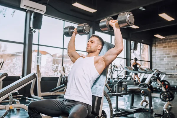 Kaslı vücut geliştirmeci biri dumbbells ile yapıyor — Stok fotoğraf