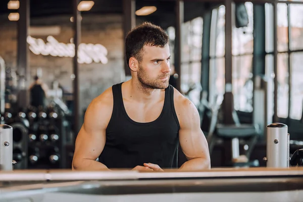 Genç adam sağlıklı kulübünde spor salonunda egzersiz sonra dinlenme