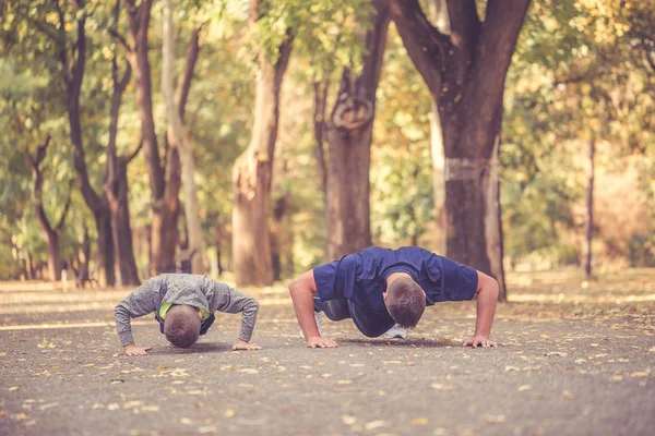 Μικρό αγόρι και ο πατέρας του κάνει push ups ασκήσεις μαζί με τ — Φωτογραφία Αρχείου