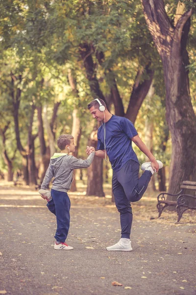 Küçük bir çocuk ve babası germe bacak egzersizleri başlayalım yapıyor — Stok fotoğraf