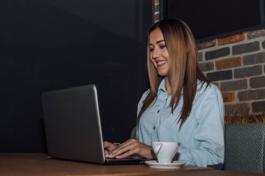 Bir kafede dizüstü bilgisayar üzerinde çalışan kadın serbest meslek