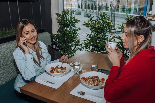 Друзья-женщины обедают вместе и разговаривают по телефону — стоковое фото