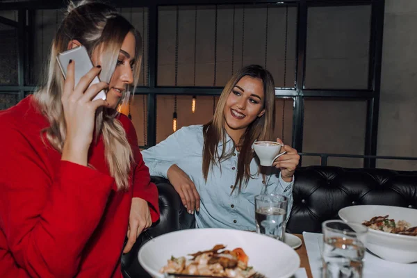 Молодая женщина разговаривает по телефону во время обеда со своей подругой — стоковое фото