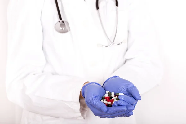 Läkare händerna i medicinska handskar håller många olika piller — Stockfoto