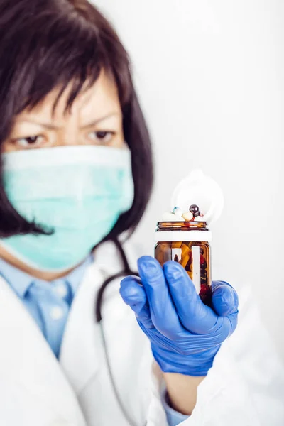 Vrouwelijke arts in de medische handschoenen houden glazen fles met vele d — Stockfoto