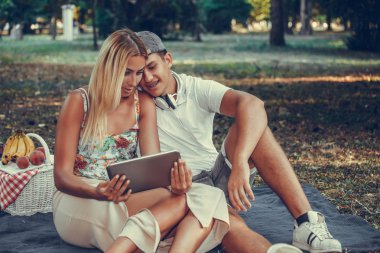 Piknik sırasında dijital tablet kullanan güzel genç çift