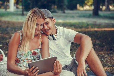 Par piknik sırasında dijital tablet kullanarak Mutlu genç çift