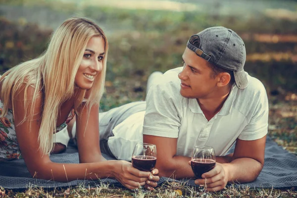 Beau jeune couple buvant du vin rouge sur un pique-nique dans le parc — Photo