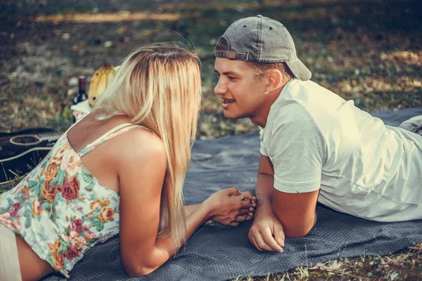 Junges Paar bei einem Picknick auf einer Decke auf dem Rasen liegend — Stockfoto