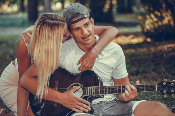 Giovane coppia divertirsi con la chitarra durante il picnic nel parco — Foto Stock