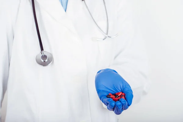 Samičí lékařka držící mnoho černě červených tobolek — Stock fotografie