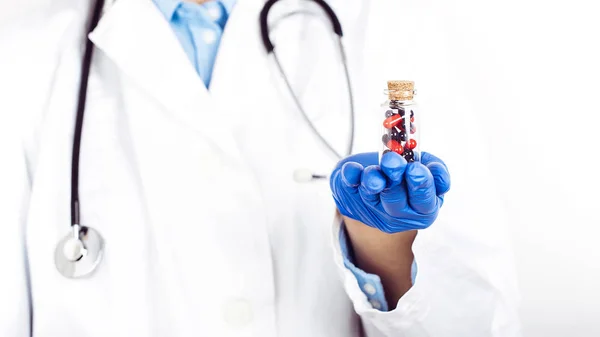 Ruce v lékařských rukavicích se skleněnou lahví s prášky — Stock fotografie
