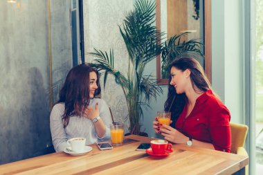 İki kadın arkadaş konuşurken ve her bakarken meyve suyu içme