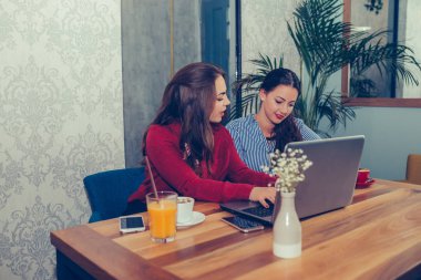 İki kız arkadaş, öğrenciler dizüstü bilgisayar kullanarak ve kahve içme