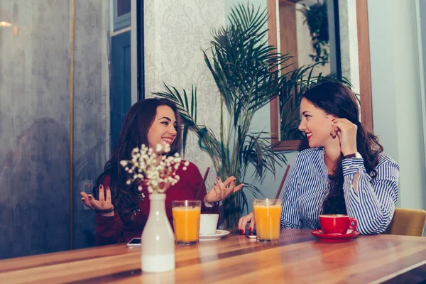 Счастливые подруги разговаривают и пьют кофе в кафе — стоковое фото