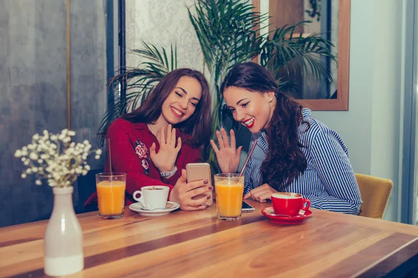 Две молодые женщины, сидящие за столиком кафе вместе и имеющие vi — стоковое фото