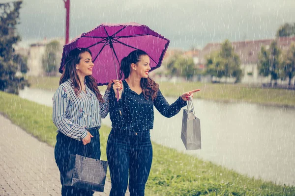 Deux meilleures amies marchant au bord de la rivière avec un parapluie au-dessus — Photo