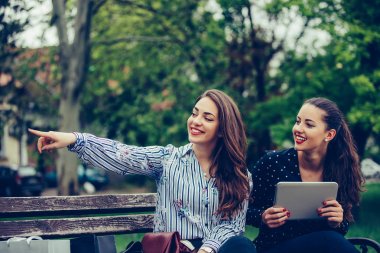 İki mutlu kadın dijital tablet tutan konum standi işaret