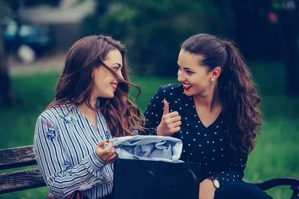 Deux belles femmes assises sur le banc du parc après avoir fait du shopping — Photo