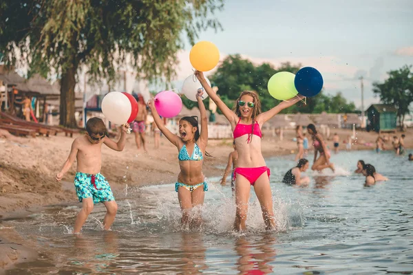 幸せな子供たちはジャンプし、水の中で風船を楽しんで、 — ストック写真