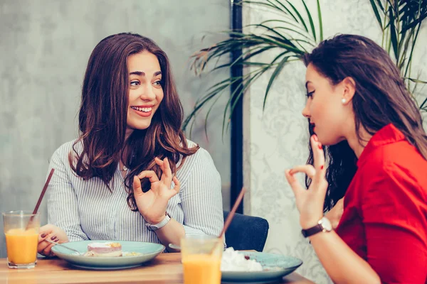 İki güzel genç kadın birlikte kek ve meyve suyu zevk bir 