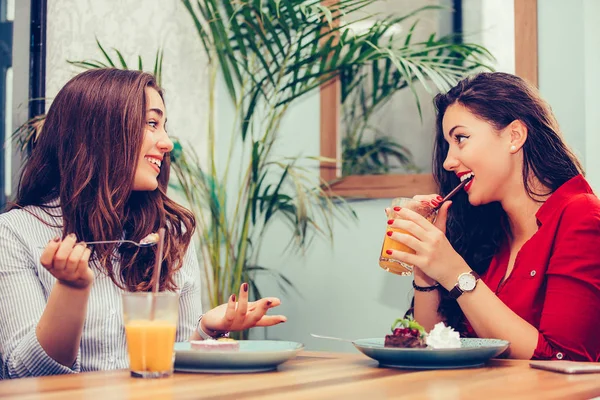 Две подруги наслаждаются тортом и соком в кафе — стоковое фото