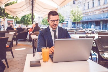 Genç adam kafede oturmuş bir video görüşmesi yapıyor. 